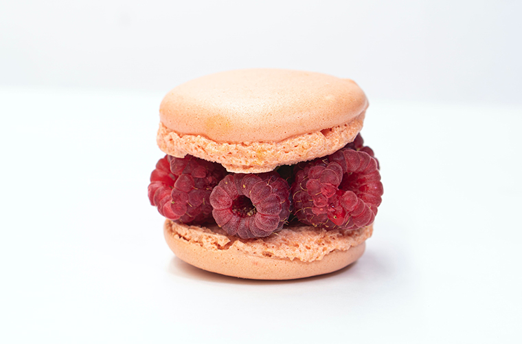 A macaron filled with fresh raspberries