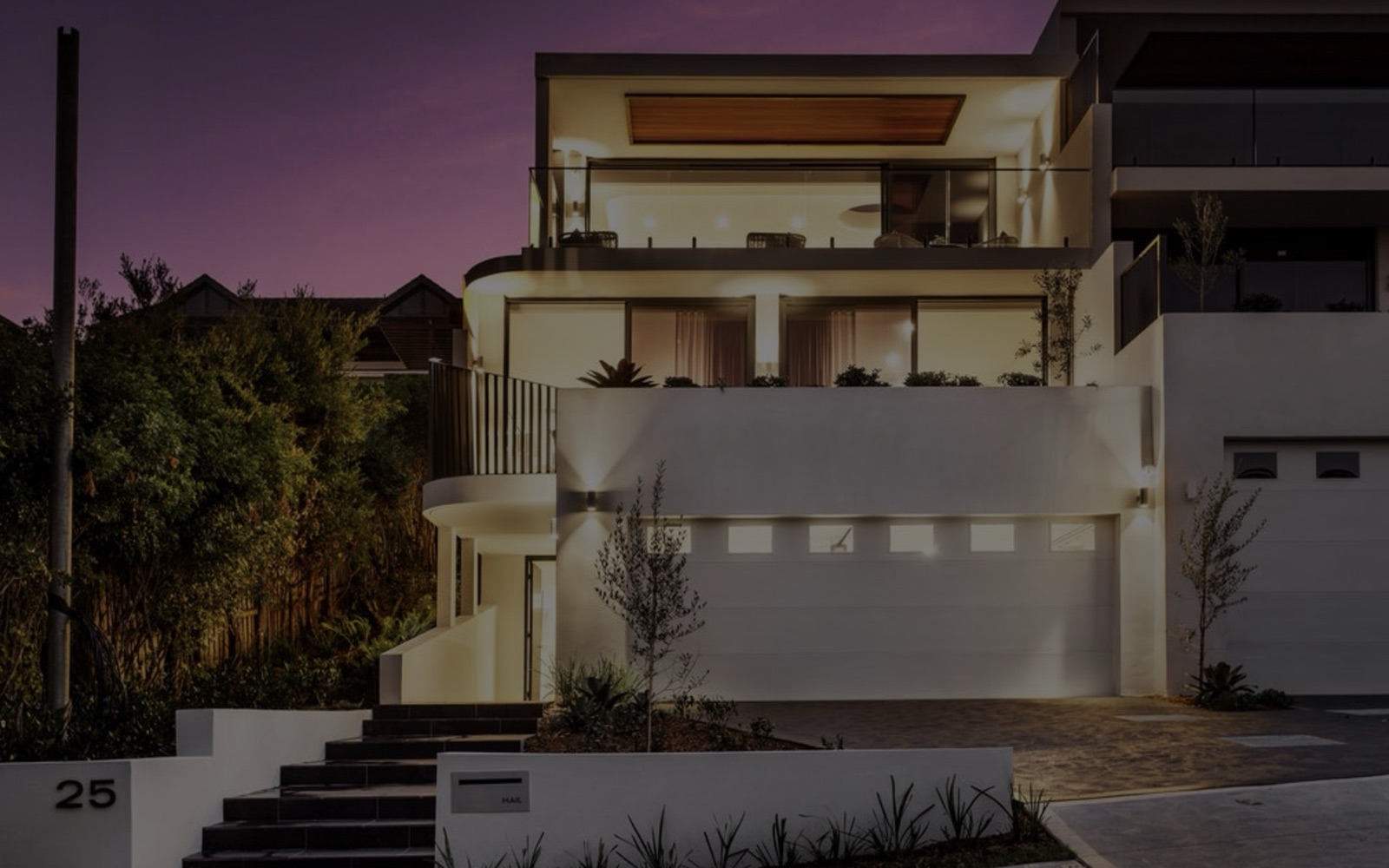 A modern Sydney home lit up at dusk, from the Oasis Skeen website