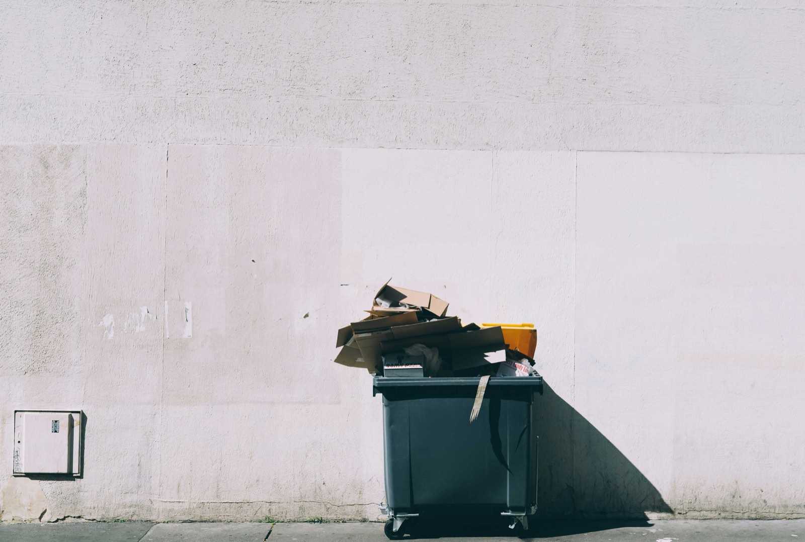 Bin of flattened cardboard against a pale wall, from the PWM website